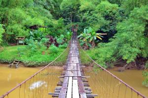un puente colgante sobre un río en un bosque en Aristo Hotel @ Putatan, en Kota Kinabalu