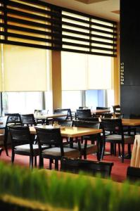 a dining room with tables and chairs and windows at Tanahmas The Sibu Hotel in Sibu