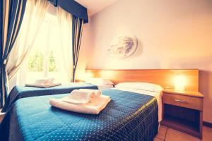 twee bedden in een hotelkamer met handdoeken erop bij Hotel La Gaietta in Millesimo