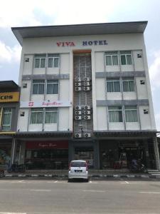 a white car parked in front of a building at VIVA HOTEL SRI AMAN in Simanggang