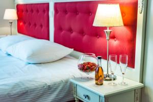 a bedroom with a bed with a red headboard and wine glasses at Hotel Sobienie Królewskie in Sobienie Szlacheckie
