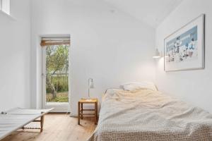 una camera da letto bianca con un letto e una finestra di Cozy Holiday Home In Tisvildeleje a Tisvildeleje