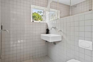 un bagno piastrellato bianco con lavandino e specchio di Cozy Holiday Home In Tisvildeleje a Tisvildeleje Altre 19 foto