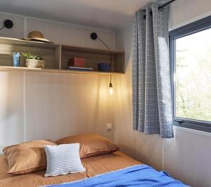a bedroom with a bed with a window and a pillow at Camping l'Oso in Porto-Vecchio
