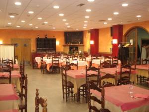 um restaurante cheio de mesas e cadeiras com toalhas de mesa vermelhas e brancas em Hostal Can Jaume em Mollerussa
