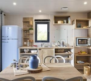 a kitchen with a table and a white refrigerator at Camping l'Oso in Porto-Vecchio
