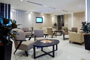 a waiting room with chairs and tables and a tv at Centrestage Petaling Jaya in Kuala Lumpur