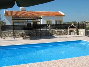 a villa with a swimming pool in front of a house at Pangeras Apartments in Pissouri