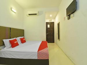 a bedroom with a bed and a flat screen tv at Capital O 90556 Hotel Cherita Rooms in Telok Baru