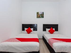 two beds in a room with red pillows at OYO 1090 Hollitel Hotel Melaka in Melaka