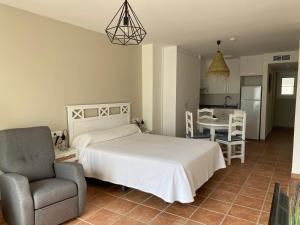a bedroom with a bed and a chair and a table at Apartahotel Vistamar San José in San José