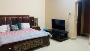 ein Schlafzimmer mit Bett und Flachbildfernseher in der Unterkunft Hyderabad bungalow in Hyderabad