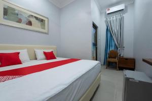 Un dormitorio con una gran cama blanca con almohadas rojas. en OYO 90234 Sungai Rengit City Resort 2, en Desaru