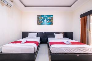 une chambre avec deux lits et un tableau au mur dans l'établissement Samudra Homestay, à Kuta