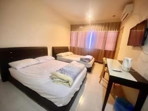 a room with two beds and a table and a desk at OYO 90381 Chaah Homestay 3 in Segamat