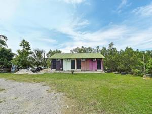a small house with a green roof on a grass field at OYO 90708 D'kuala Waterfront Chalet & Boat Charters in Kampong Aman