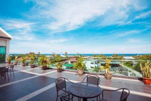 a balcony with tables and chairs and a view of the ocean at Friendly Hotel in Kudat