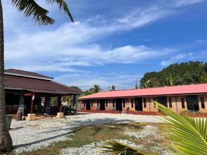 a building with a red roof and a palm tree at OYO 90818 Cemara Puri Resort & Spa in Kampong Pantai Batu Hitam +18 photos