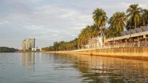 a body of water with palm trees and buildings at Nyamanya Inn Kuantan in Kampong Alor Akar