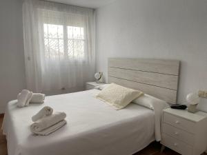 a bedroom with a white bed with towels on it at Apartahotel Vistamar San José in San José
