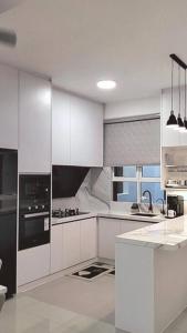 a kitchen with white cabinets and a black appliance at Meraki Homestay Ladang Tanjung in Kuala Terengganu