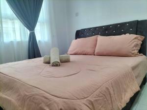 a large bed with pink sheets and pillows on it at Meraki Homestay Ladang Tanjung in Kuala Terengganu