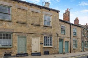 un vecchio edificio in mattoni con porte e finestre verdi di Castle Yard Cottage a Knaresborough