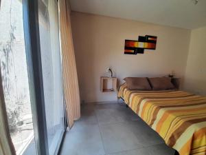 een slaapkamer met een bed en een groot raam bij Casa El Almendro-Barrio Privado - Para 2 personas in Ciudad Lujan de Cuyo +24 foto's