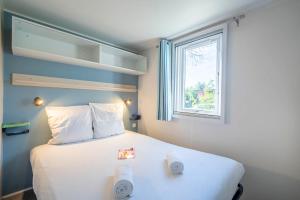 a bedroom with a large white bed with a window at Camping Paradis 4 étoiles A La Corniche La Rochelle Angoulins in Angoulins-sur-Mer