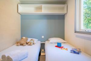 two beds in a room with two teddy bears on them at Camping Paradis 4 étoiles A La Corniche La Rochelle Angoulins in Angoulins-sur-Mer