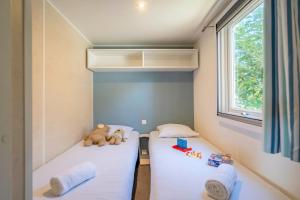 two beds in a small room with a teddy bear on them at Camping Paradis 4 étoiles A La Corniche La Rochelle Angoulins in Angoulins-sur-Mer