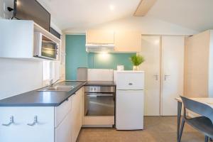 a kitchen with white cabinets and a sink and a table at Camping Paradis 4 étoiles A La Corniche La Rochelle Angoulins in Angoulins-sur-Mer