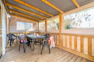 a dining room with a table and chairs on a porch at Camping Paradis 4 étoiles A La Corniche La Rochelle Angoulins in Angoulins-sur-Mer