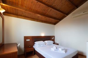 a bedroom with a bed with white sheets and wooden ceilings at Dia Apartments in Hersonissos