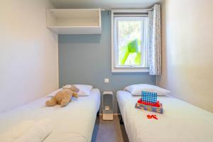 two beds in a room with a teddy bear on the bed at Camping Paradis 4 étoiles A La Corniche La Rochelle Angoulins in Angoulins-sur-Mer