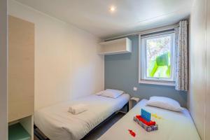 two beds in a small room with a window at Camping Paradis 4 étoiles A La Corniche La Rochelle Angoulins in Angoulins-sur-Mer