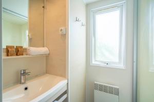 a bathroom with a sink and a window at Camping Paradis 4 étoiles A La Corniche La Rochelle Angoulins in Angoulins-sur-Mer