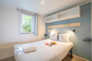 a bedroom with a white bed with a hat on it at Camping Paradis 4 étoiles A La Corniche La Rochelle Angoulins in Angoulins-sur-Mer