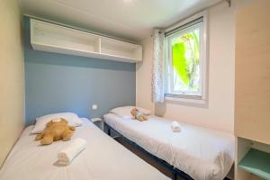 two beds in a room with two teddy bears on them at Camping Paradis 4 étoiles A La Corniche La Rochelle Angoulins in Angoulins-sur-Mer