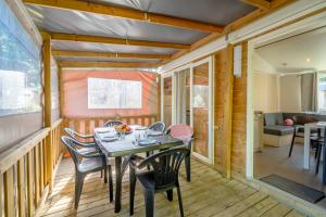 a dining room with a table and chairs on a deck at Camping Paradis 4 étoiles A La Corniche La Rochelle Angoulins in Angoulins-sur-Mer