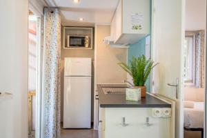 a small kitchen with a refrigerator and a sink at Camping Paradis 4 étoiles A La Corniche La Rochelle Angoulins in Angoulins-sur-Mer