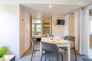 a dining room with a white table and chairs at Camping Paradis 4 étoiles A La Corniche La Rochelle Angoulins in Angoulins-sur-Mer