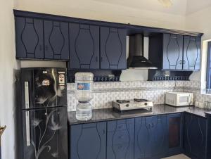 a kitchen with blue cabinets and a black refrigerator at Indeevaram Apartments in Kovalam