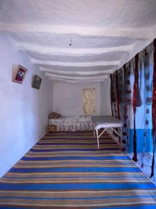 a room with a bed and a striped carpet at The Endless Enigma in Tazroutane