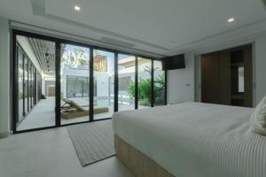 - une chambre avec un grand lit et de grandes baies vitrées dans l'établissement Fully renovated Pool Villa 4BR Bangtao and Layan Beach in Cheong Thalea, Phuket, à Phuket 58 autres photos