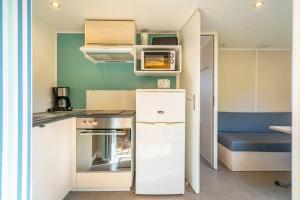 a small kitchen with a stove and a refrigerator at Camping Paradis 4 étoiles A La Corniche La Rochelle Angoulins in Angoulins-sur-Mer