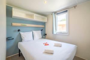 a bedroom with a large white bed with a window at Camping Paradis 4 étoiles A La Corniche La Rochelle Angoulins in Angoulins-sur-Mer