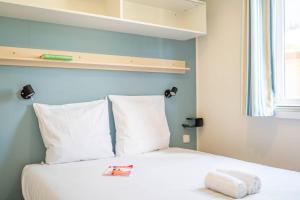 a bed with white sheets and pillows in a room at Camping Paradis 4 étoiles A La Corniche La Rochelle Angoulins in Angoulins-sur-Mer