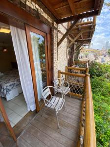 a balcony of a house with a bed and chairs at Pousada Manga Rosa Beira Mar in Natal
