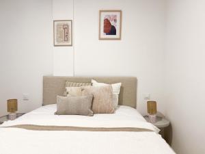 Un dormitorio con una cama con sábanas blancas y dos lámparas. en TAYP San Marcos 102, en Talayuela